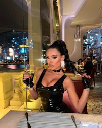 a woman in a black leather dress sitting at a table